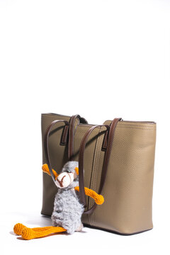 Women's beige leather bag with a toy on a white background