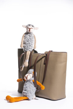 Women's beige leather bag with a toy on a white background