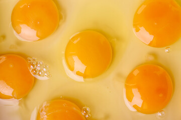 Fresh raw eggs with visible yolks on light background