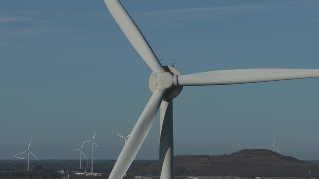 Aerial, reveal, big windmill, wind turbine standing near Albert canal during winter. Houses between trees. Other turbines in background. slag heap. Clean energy technology, geen energy, no emission.