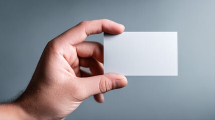 Fototapeta premium Hand Holding Blank Business Card Mockup for Design Presentation Against Neutral Background