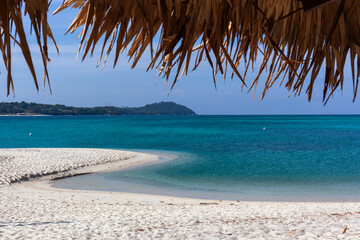 Naklejka premium Tropical beach in Koh Adang, Thailand, with turquoise waters and sandy shoreline under a palm-thatched roof.