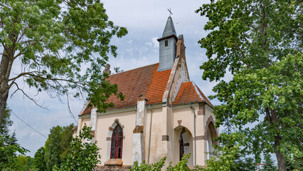 Small Catholic Church in Viazyń village among green trees with copy space