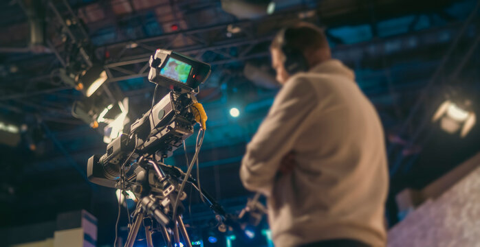 Professional TV camera in studio filming broadcast with cameraman on background and copy space