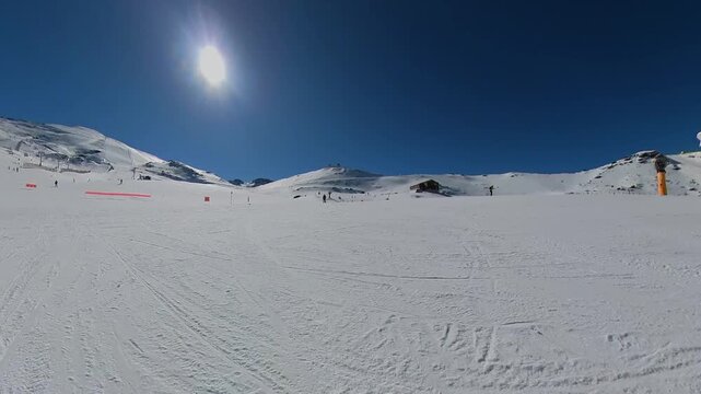 4K Cinematic drone footage of the Veleta peak slopes in Sierra Nevada, Spain, showcasing the vast snowy mountain side under a bright, clear sun