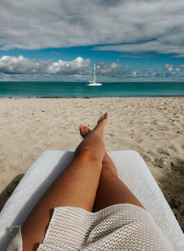 Woman's legs on beach lounge chair overlooking tropical ocean.