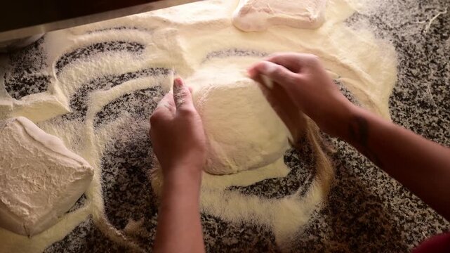 Professional pizza maker preparing dough on a floured countertop