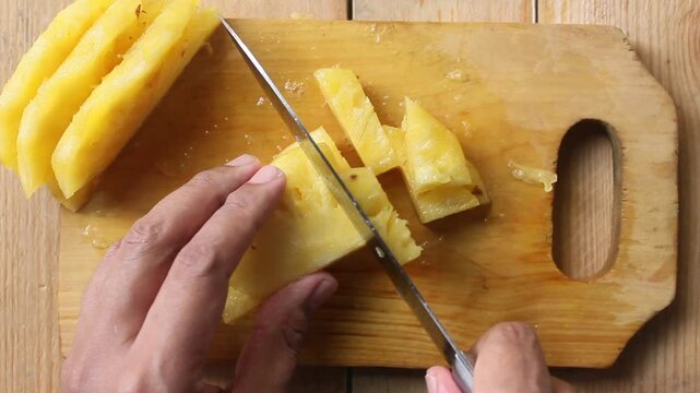 top view of slicing pineapple on a cutting board