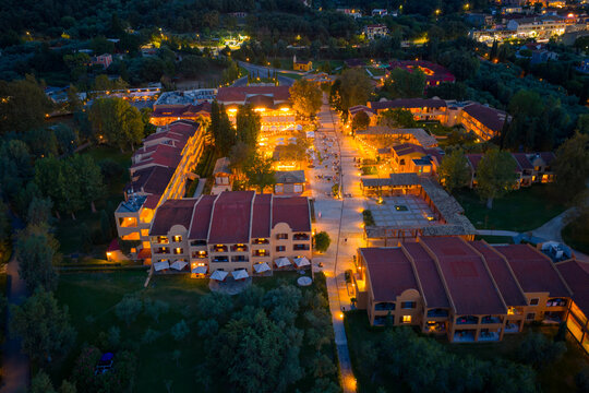 Evening aerial shot of the luxurious Grecotel Costa Botanica resort in Corfu, Greece, with the central piazza and hotel wings warmly illuminated