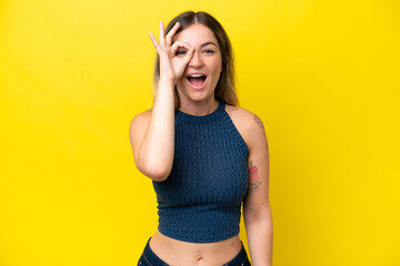 Young Rumanian woman isolated on yellow background showing ok sign with fingers