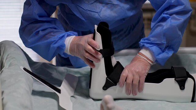 Doctor Fixing Orthopedic Boot on Patient in Bed. Doctor hands adjusting a white stabilizer boot on a patient foot. Postoperative care or injury management in a professional medical ward