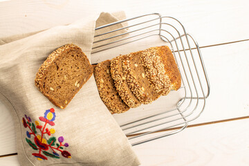Grain bread in a basket on a wooden table, close-up, top view.