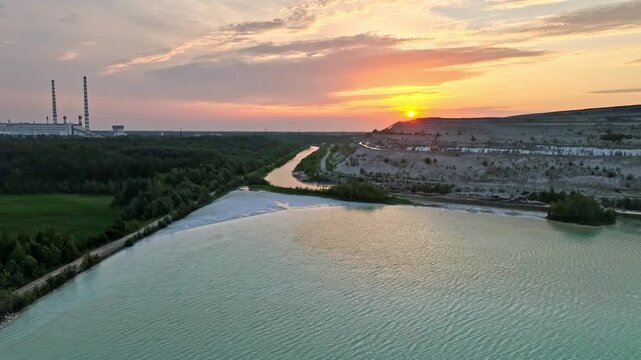 Aerial sunset still video of Auvere Power Plant Settlement Basin in Ida-Viru County, Estonia. Turquoise ash pond, industrial chimneys and limestone hill create a striking contrast. 