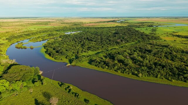 Aerial drone footage flying over the vast colombian plains, revealing a winding river and dense forest