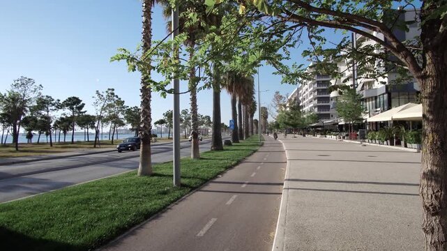 Sunny street alongside beach with bike path and palm trees in Vlore, Albania