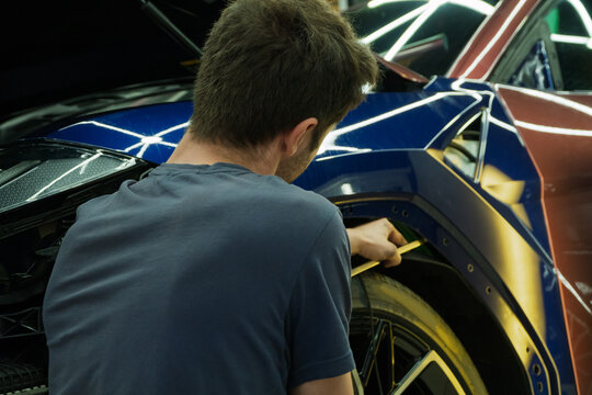 Process of paintless dent repair on car body. The mechanic at the auto shop with tools to repair dents in car body. Body repair. A specialist repairs a dent on the car body without painting. PDR.