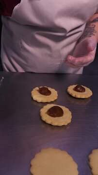 We prepare shortbread cookies. Carefully cut out delicious cookie molds by hand from the rolled dough. Vertical video.
