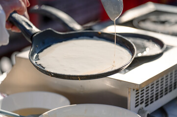 Fototapeta premium Chef pouring batter into frying pan for cooking pancakes outdoors