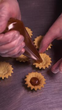 The pastry chef spreads jam on cookies. Vertical video.