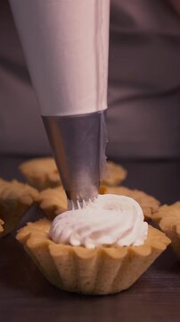 The pastry chef spreads jam on cookies. Vertical video.