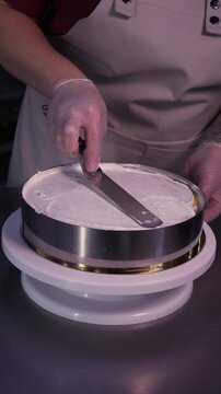 The process of making sponge cake. The concept of making confectionery desserts. The pastry chef applies the cream to the cakes.