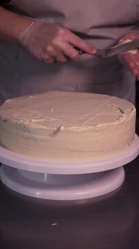 The process of making sponge cake. The concept of making confectionery desserts. The pastry chef applies the cream to the cakes.