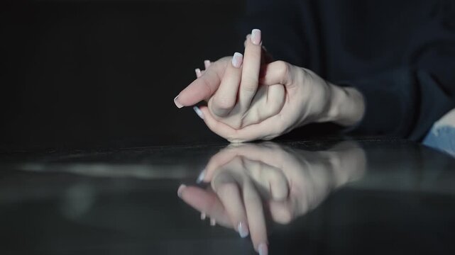 Anxious woman cracking knuckles hand fingers with reflection showing thoughtful or contemplative gesture