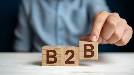Naklejka premium Business to business concept on wooden cubes, business hand putting last wooden cube with letter b to complete b2b word on table background