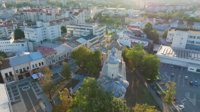 Drone orbit over old town of Botosani, church in glowing sunset, landmark of Romania - aerial 4k