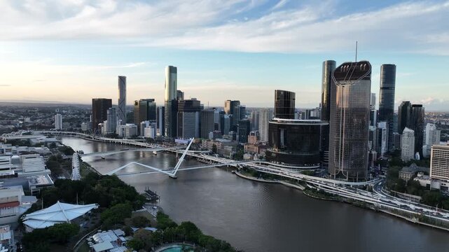 Steady drone shot at golden hour over the Brisbane River, holding Queens Wharf and The Star Brisbane towers with Neville Bonner Bridge and the CBD skyline, Brisbane, QLD, Australia