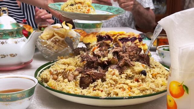 Uzbek family at festive Eid table with plov, tea and samsa, close-up
