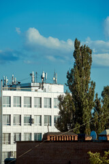 Obraz premium A multi-story building above the treetops in the city in summer, photographed from the roof of another building