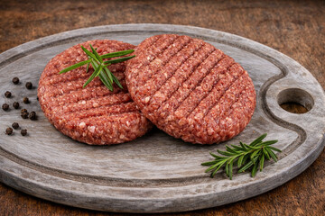 Steaks hachés de boeuf crus sur une planche à découper