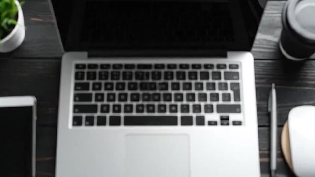 Top view of a modern workspace with a laptop, smartphone, and coffee cup on