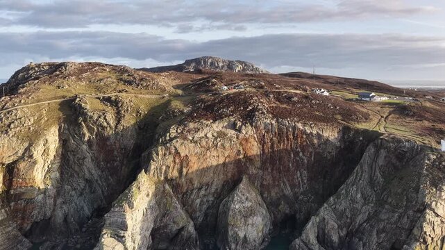 Aerial drone footage of South Stack Lighthouse on the rugged Welsh coast, dramatic cliffs and Atlantic waves, cinematic seascape ideal for travel, nature, coastal tourism and documentary use.