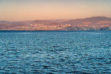 Obraz premium The coastal city of Eilat with the Israeli flag on the coast at sunrise.