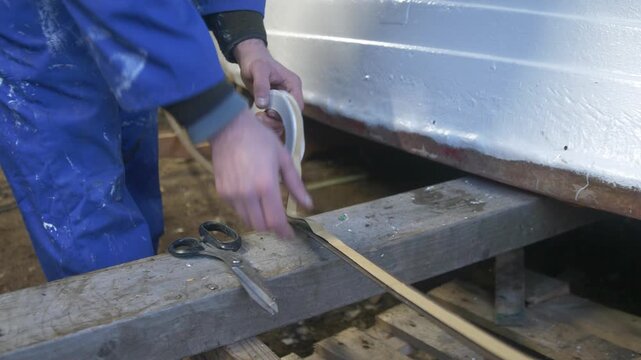 Applying butyl rubber tape to steel keel band for boat repair