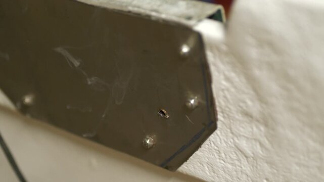Smoking drill bit penetrates stainless steel plate metal