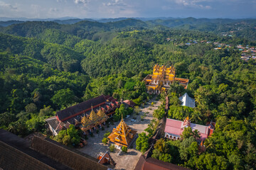 Obraz premium Aerial view of Wat Wang Wiwekaram temple surrounded by lush green forest and scenic lake in Sangkhlaburi, Kanchanaburi, Thailand during golden hour
