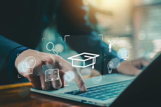 Online education concept with businessman using laptop and touching virtual graduation cap icon, e learning platform, digital training, knowledge management and smart technology interface.