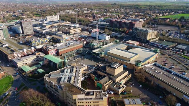 Reverse aerial view shows Basildon, UK, cityscape with roads, buildings and green spaces