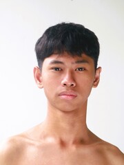 Naklejka premium Portrait of a young South East Asian Indonesian boy with a funny face expression against a plain white background
