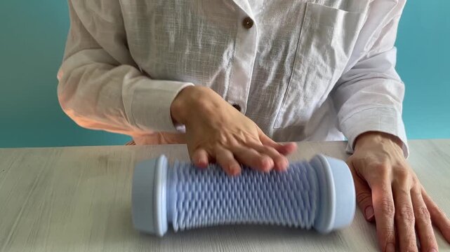 hands pressing a small acupressure finger massager over fingertips and palm with repetitive tactile sounds, concept of sensory therapy, stress relief, mindfulness, self care