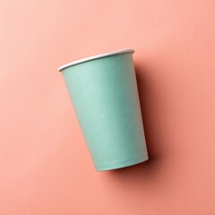 A teal colored disposable paper cup on a peach background