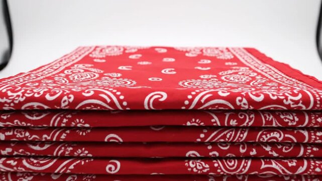Stack of red paisley patterned bandanas on a white background