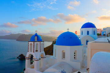 Obraz premium traditional white greek village Oia of Santorini, with blue domes of churches in sunset light, Greece