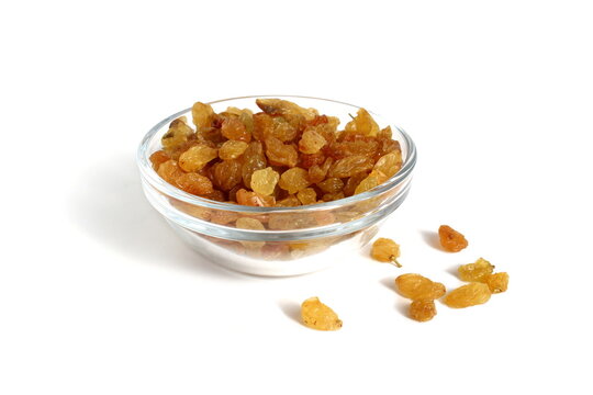 There is a glass bowl with yellow raisins on a white background.