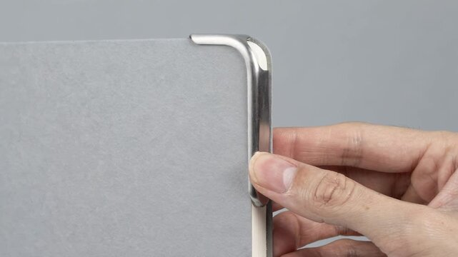 Medium shot focusing on rounded metal protectors being installed on a blankbook corner showcasing smooth finishes and added safety for frequent use.