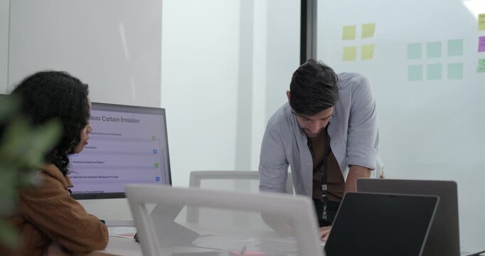 Diverse group of startup team engaging in brainstorming session, using sticky notes on glass wall to organize ideas, plan next steps. Creativity and collaborative spirit of modern entrepreneurial team