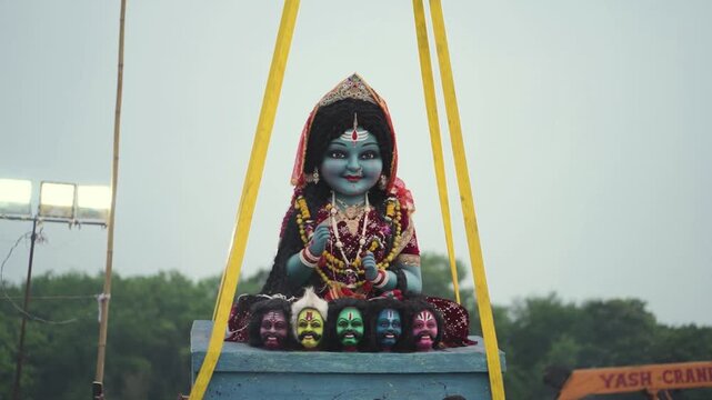 Mata Rani idol immersion ceremony, Crane lifting Durga idol for visarjan, Hindu festival idol immersion scene, Goddess statue during visarjan ritual stock video.